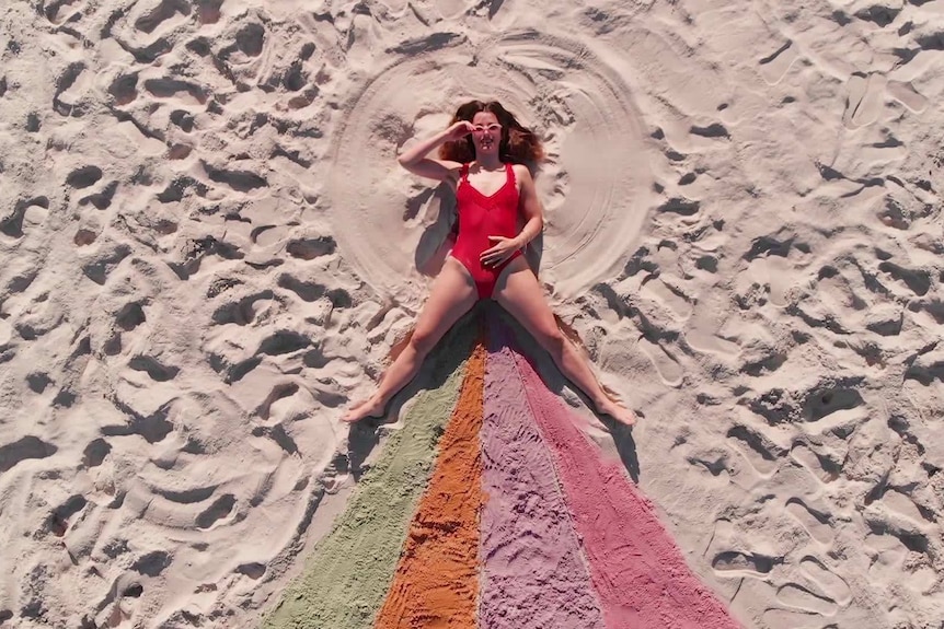 Peach lays in the sand where a rainbow appears in the lower part of the frame.