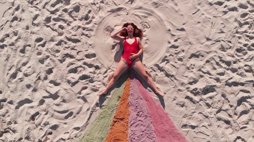 Peach lays in the sand where a rainbow appears in the lower part of the frame.