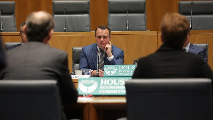 Tim Wilson rests his head on his hand as he listens to testimony from two people