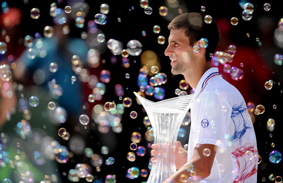 Novak Djokovic holds the winner's trophy and watches the bubbles after winning in Key Biscayne.