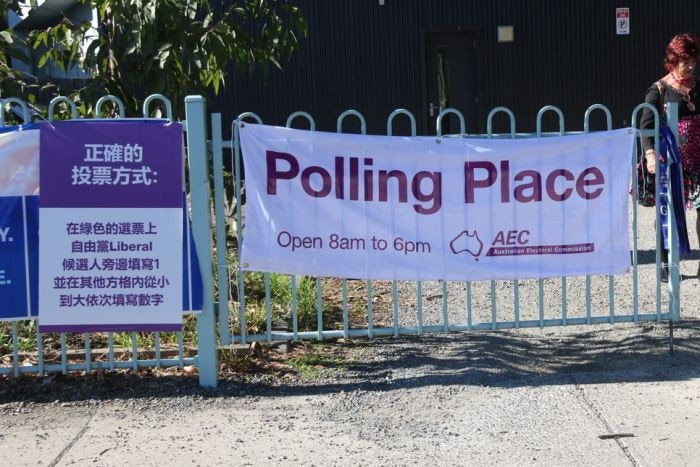 A poster in Mandarin next to an official AEC sign. Both have similar purple and white colours