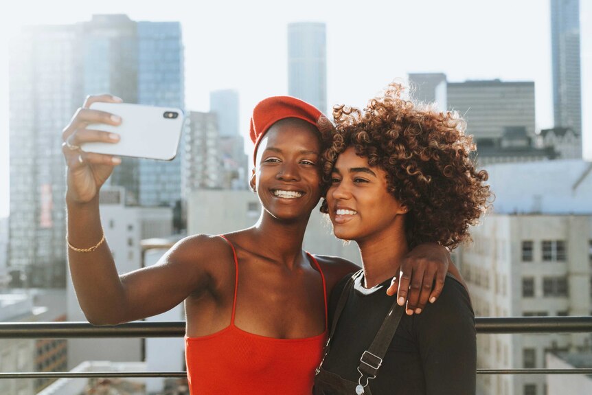 Two teenagers smile and take a selfie