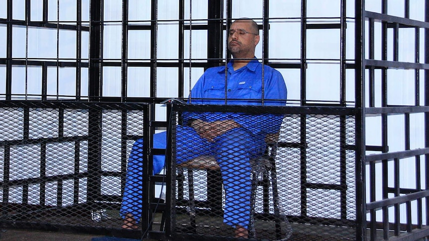 Saif al-Islam Gaddafi attends a hearing behind bars.