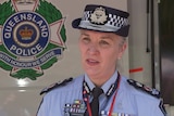 Queensland Police Service Commissioner Katarina Carroll wearing uniform next to service emblem on vehicle