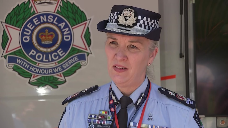 Queensland Police Service Commissioner Katarina Carroll wearing uniform next to service emblem on vehicle