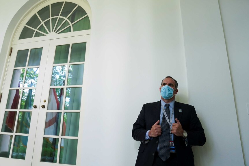 A US Secret Service member wears a protective face while standing next to a door