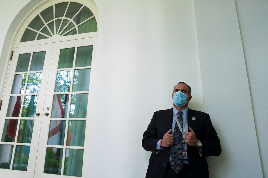 A US Secret Service member wears a protective face while standing next to a door