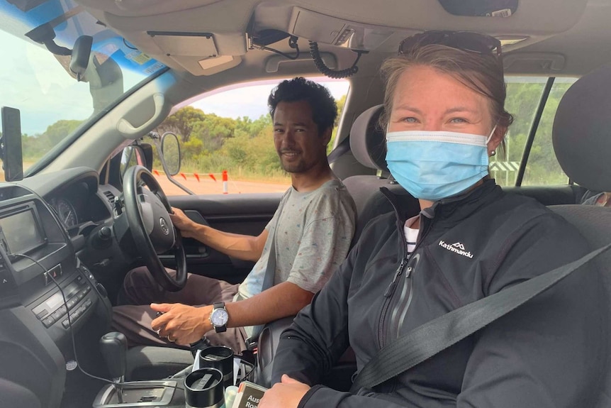 A man and woman stop for a photo while sitting inside a four wheel drive