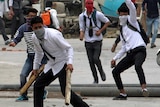Kashmir school students in their uniforms, wearing backpacks, brandish sticks and throw rocks at Indian security forces.