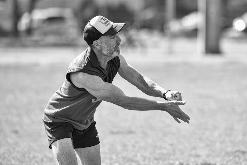 A man holds his arms out after hand balling in a game of Aussie Rules.