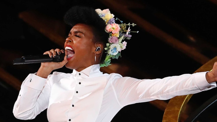Janelle Monae singing into a microphone
