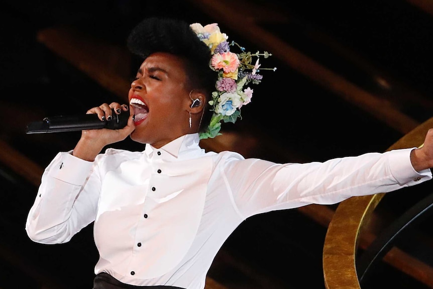 Janelle Monae singing into a microphone