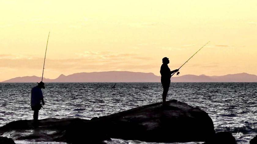 Two fishermen wait for a bite at dusk