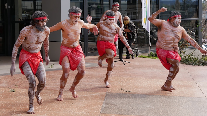 A group of Indigenous dancers dancing outside a building