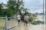 Two men carry dogs through floodwater