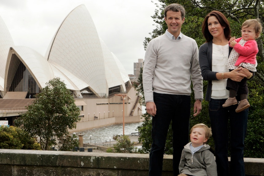 A family take a photo in front of the Sydney Opera House 