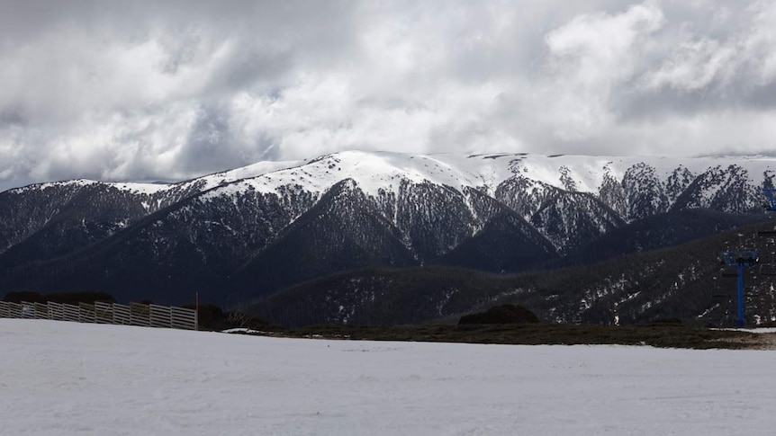 an alpine landscape with fresh snow in the foreground and snowcapped mountains on the horizon