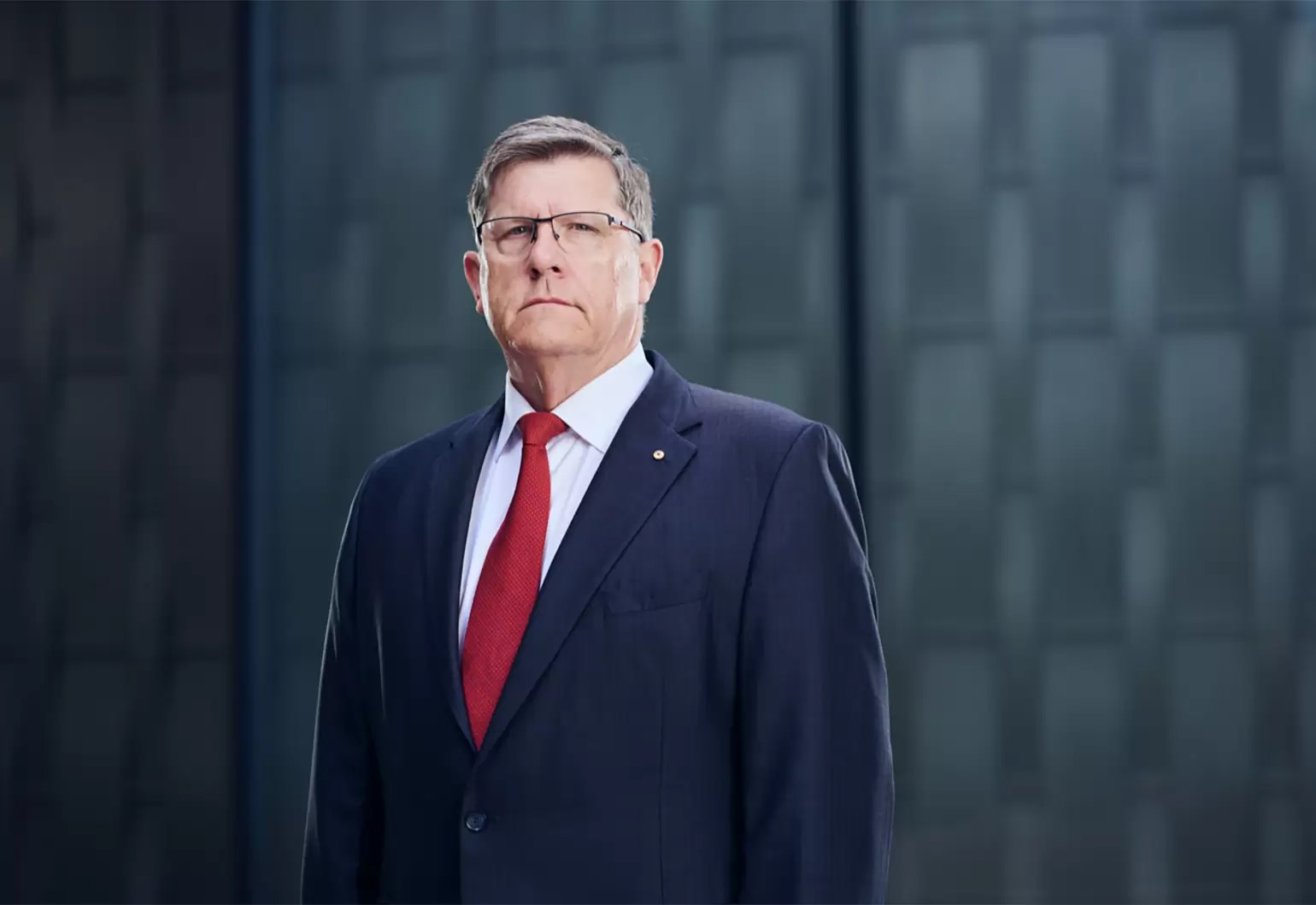 A man in a suit looks at the camera