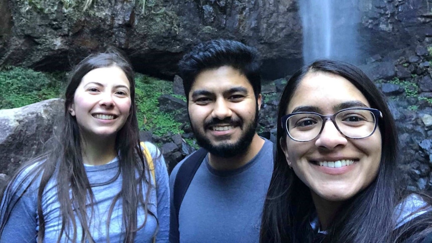 three people standing in front of a waterfall smiling