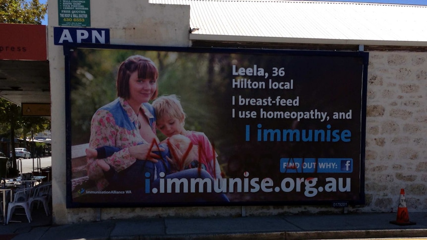 Anti-immunisation activists graffiti a billboard in Fremantle