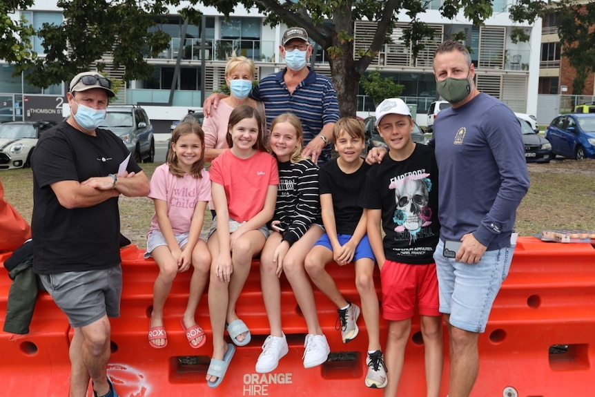 Two families and several children meet up at an orange barrier.