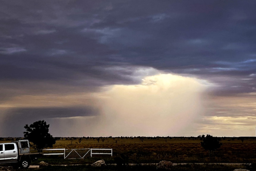 Landscape of light breaking through a cloud with a ute in the foreground.