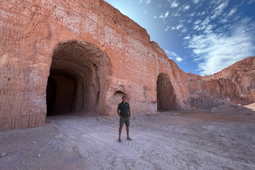 hombre de pie cerca de la cueva que parece serio 