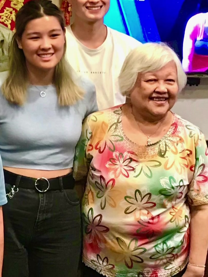 A young woman stands next to her grandmother.