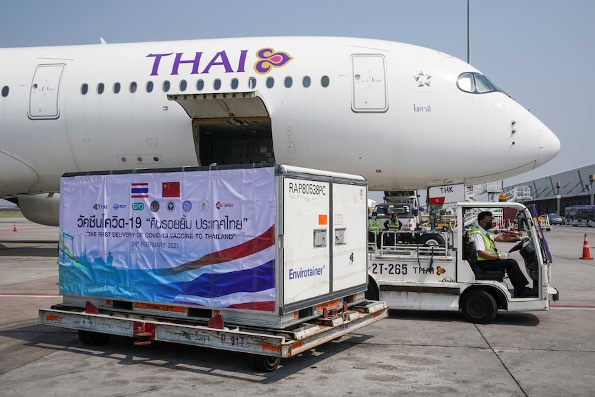 A container labelled "The first delivery of COVID-19 vaccine to Thailand" is unloaded from a Thai plane.