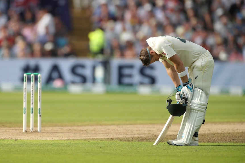 A batsman catches his breath, bent over with hands on knees, after scoring a Test century.