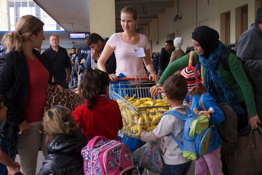 A Viennese volunteer distributes fruit to asylum seekers waiting for news on when, or if, they will be able to continue their journeys out of Austria
