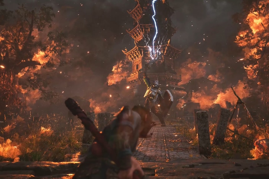 Zrzut ekranu przedstawiający głównego bohatera Black Myth: Wukong w obliczu ogromnego wroga stojącego w pobliżu płonącej wioski i świątyni.