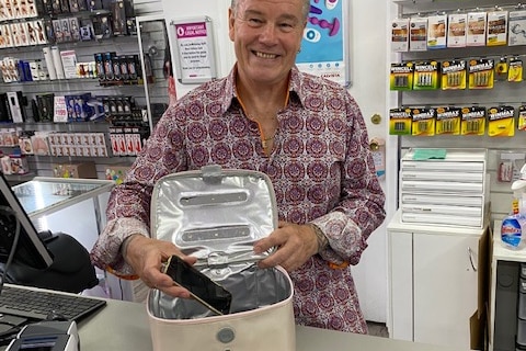 A man places a phone in a UV sanitation bag