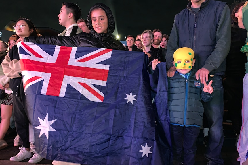 a young football fan holds an australian flag