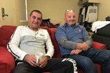 Two men sit on a couch in a shared house