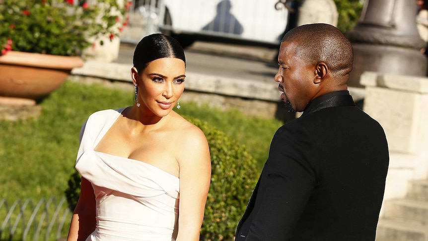 Kim Kardashian and Kanye West pose in formalwear in a garden.