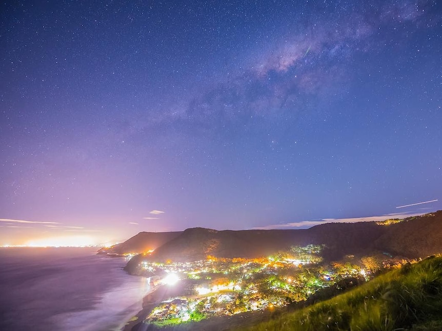 Starry night above twinkling coastline