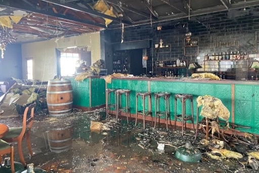 A fire damaged bar with wine barrel and wine stools. 