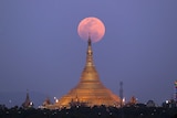 The moon rises behind the Uppatasanti Pagoda seen from Naypyitaw, Myanmar.