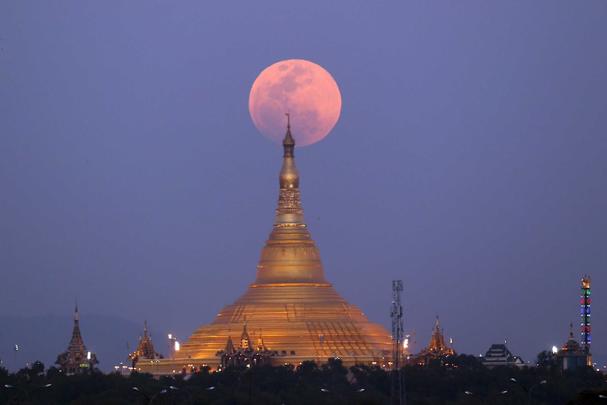 The moon rises behind the Uppatasanti Pagoda seen from Naypyitaw, Myanmar.