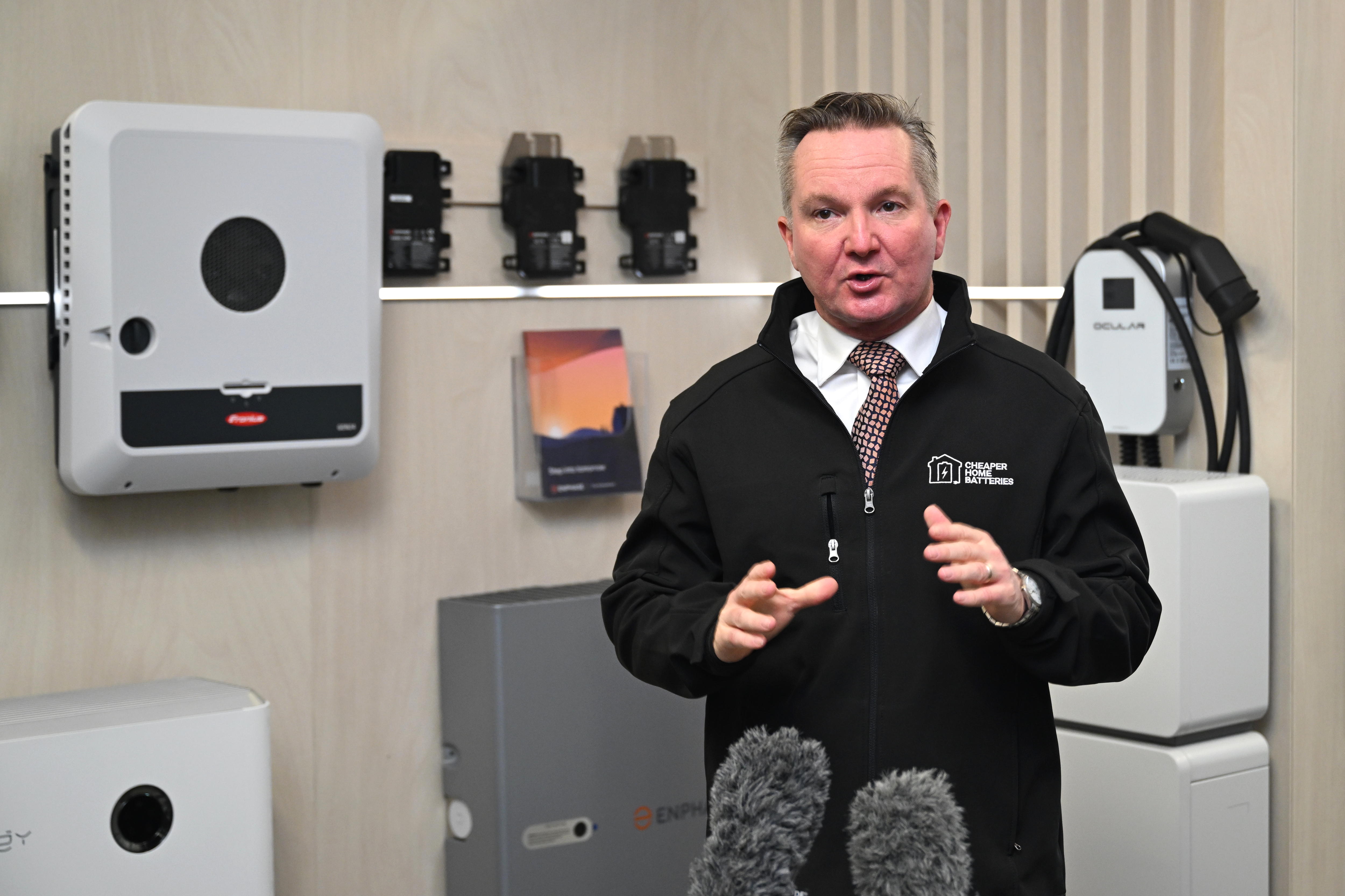 Bowen stands in a garage, a wall battery beside him.