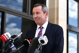 Mark McGowan in front of media microphones outside parliament.