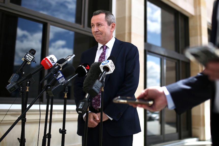 Mark McGowan in front of media microphones outside parliament.