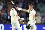 Two Australian male cricketers embrace as they celebrate a century against West Indies in Adelaide.