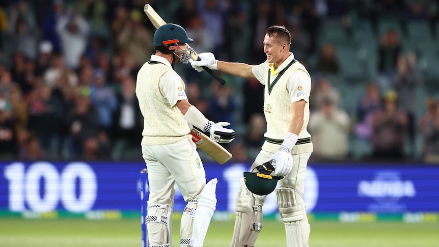 Two Australian male cricketers embrace as they celebrate a century against West Indies in Adelaide.