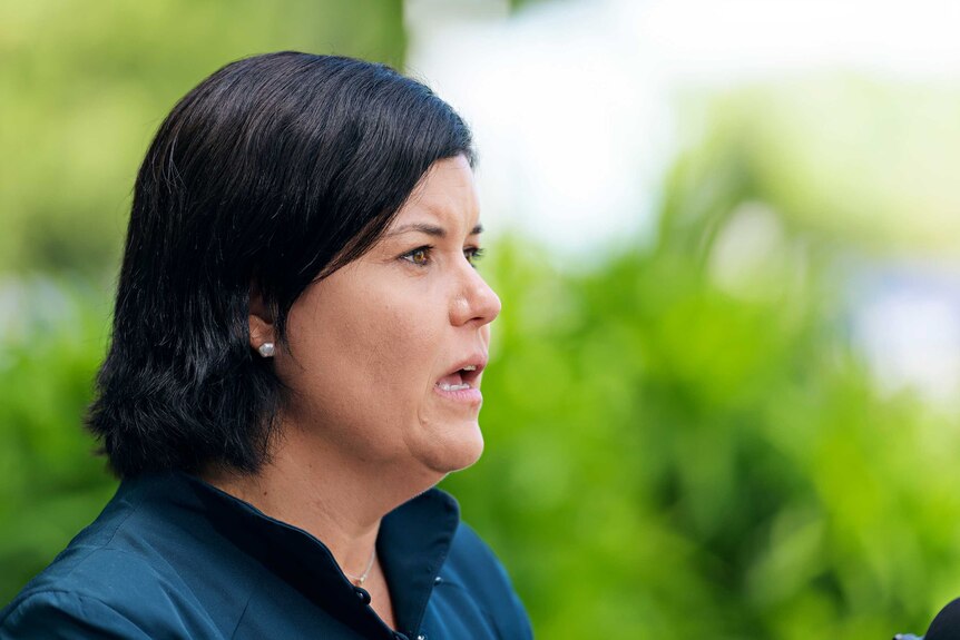 A side-on shot of Chief Minister Natasha Fyles speaking to the media. She has collar-length dark, straight hair and a blue top.