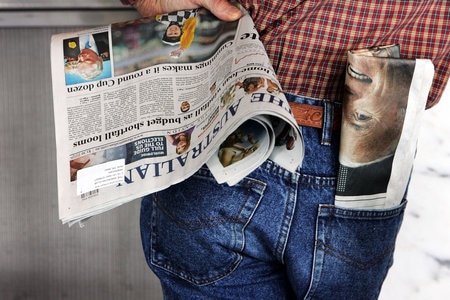 A man holding The Australian newspaper