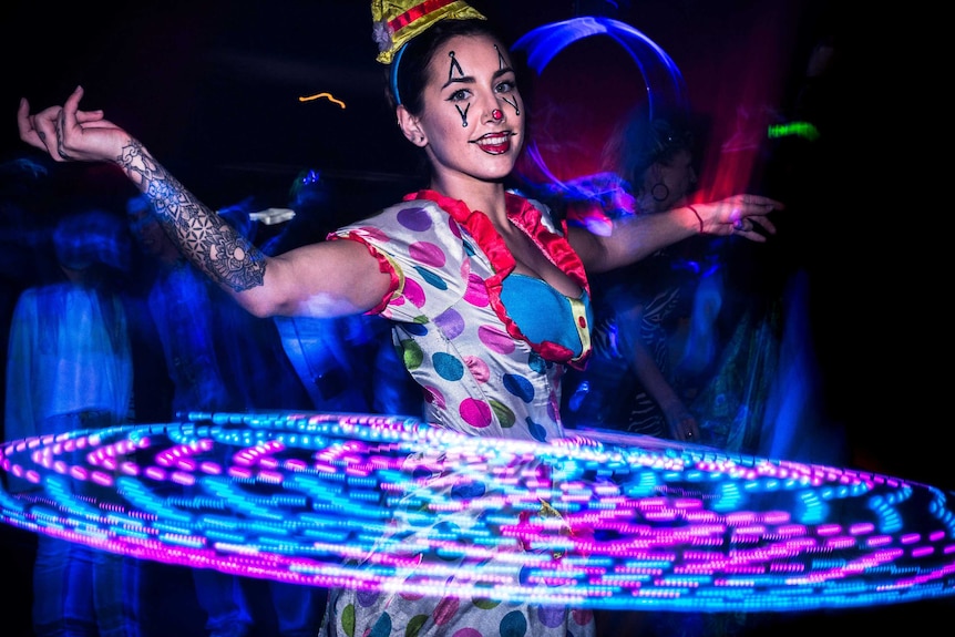 a woman in a clown costume hula-hooping in the dark