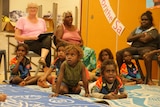 Small Aboriginal children in classroom on mat with adults sitting in chairs