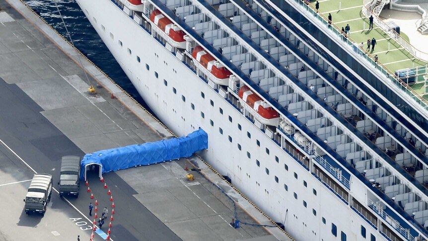 A cruise ship with a walkway from the door covered in blue tarps